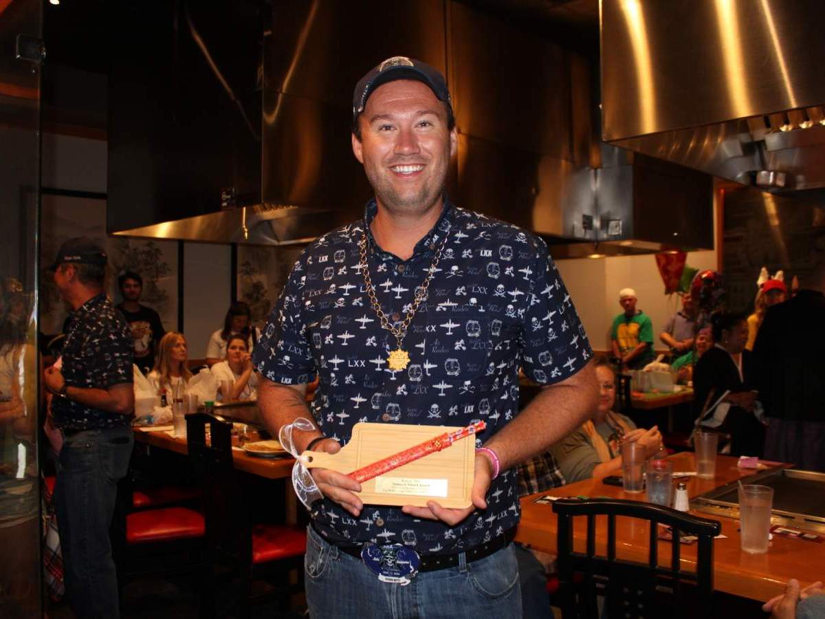 Person in hat holding custom cutting board and chopsticks